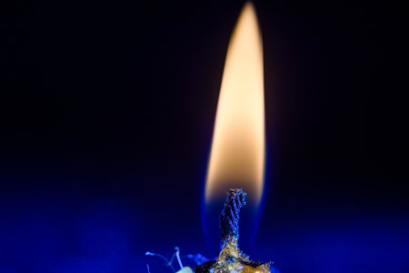 A burning candle against a dark background close-up.の写真素材
