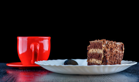 Chocolate cake and red cup of coffee on wooden table, black backgroundの写真素材