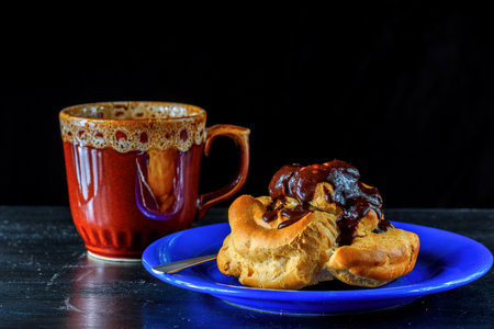 Cup of coffee and croissant with chocolate on black background