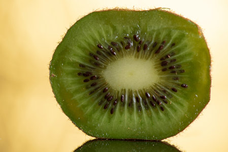 Kiwi fruit close-up on a yellow background with reflectionの写真素材