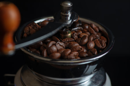 Coffee grinder with coffee beans on a black background.の写真素材