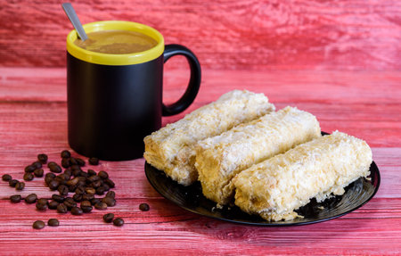 Napoleon cakes and a cup of coffee on a red wooden background.の写真素材