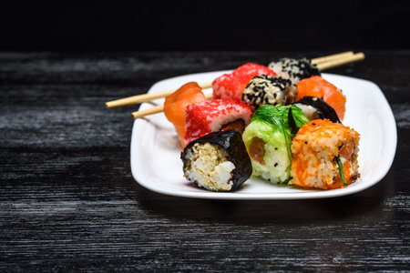 Sushi on a plate on a black wooden background.の写真素材