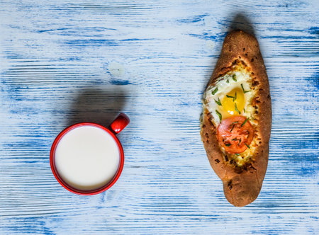 Cup of milk with egg and tomato sandwich on blue wooden backgroundの写真素材