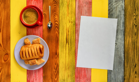 puff pastry on a plate and coffee mug on a multi-colored wooden backgroundの写真素材