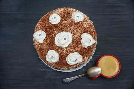 Tiramisu cake with whipped cream and cup of coffee on dark wooden background, top viewの写真素材