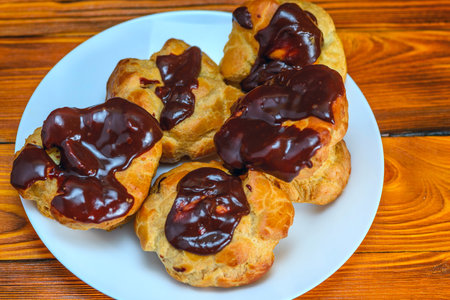 Profiteroles with chocolate glaze on a plate on a wooden table