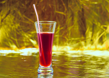A glass of red juice on a gold background.の写真素材
