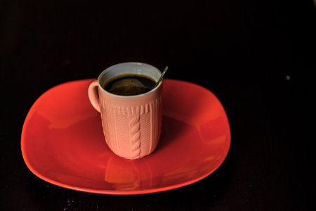 coffee mug on a red plate close up on a dark backgroundの写真素材