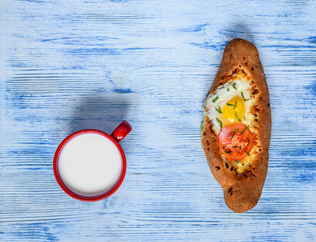 Cup of milk and crostini with egg and tomato on blue wooden backgroundの写真素材