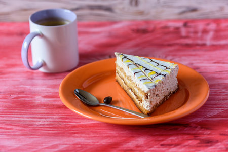 Sponge cake on a wooden background photographed on a ceramic plate of orange color.の写真素材