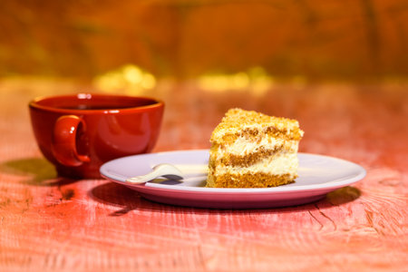 A slice of sponge cake with walnuts, next to a cup of coffee.