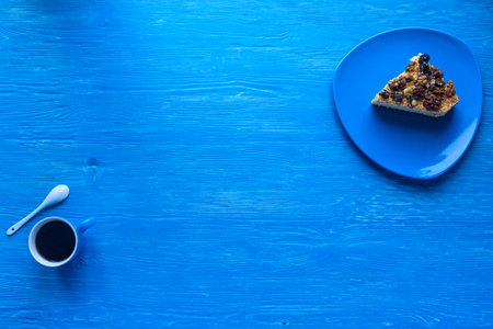 Sponge cake with walnuts, next to a cup of coffee on a wooden background, photographed from above.の写真素材