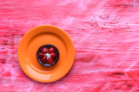 A strawberry dessert on a plate photographed on a wooden background from the top.の写真素材