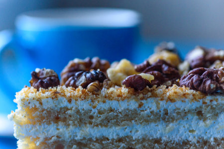 Walnut sponge cake slice photographed close-up on a turquoise plate, on wooden background.の写真素材