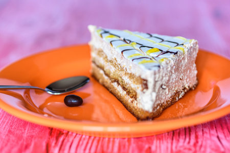 Sponge cake on a wooden background photographed on a ceramic plate of orange color.