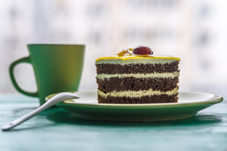 Chocolate puff cake with cherry on top and a cup of coffee photographed close-up on a wooden...
