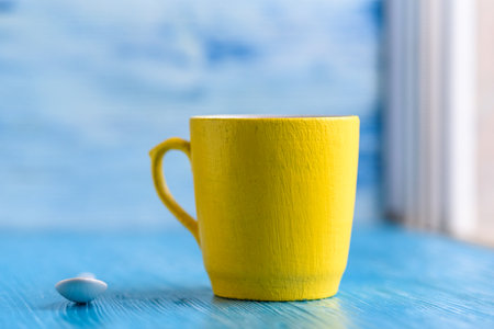 Yellow mug on a blue background photographed close-up.の写真素材