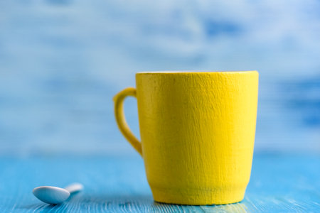 Yellow mug on a blue wooden background photographed close-up.の写真素材