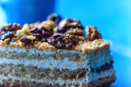 Walnut sponge cake slice photographed close-up on a turquoise plate, on wooden background.の写真素材