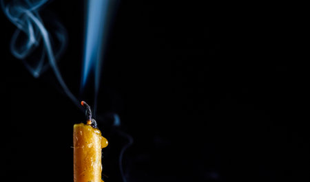 Burning candle with smoke on black background, closeup. Space for textの写真素材