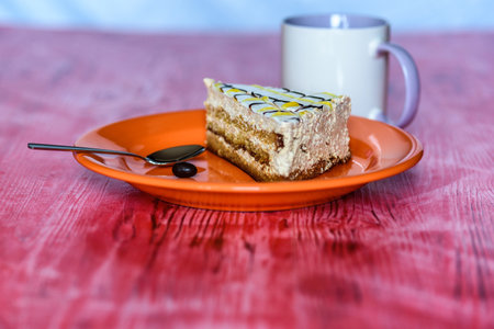 Sponge cake on a wooden background photographed on a ceramic plate of orange color.