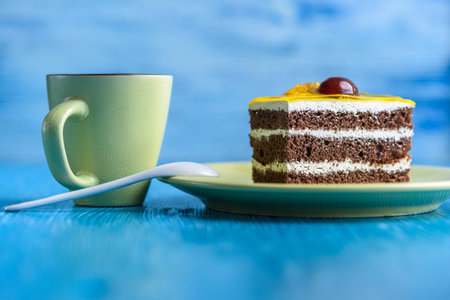 Chocolate puff cake with cherry on top and a cup of coffee photographed close-up on a wooden background.の写真素材