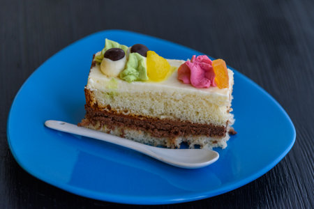 Cake with cream photographed close-up on a blue plate on a wooden background.の写真素材