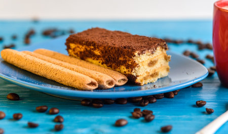Tiramisu cake on a plate, near a cup of coffee.の写真素材