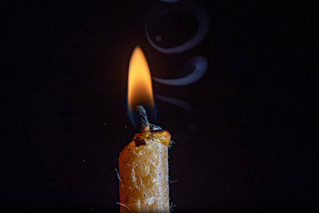 The flame of a burning candle against a dark background.の写真素材