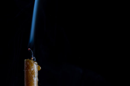 Burning candle with smoke on black background. Shallow depth of field.の写真素材
