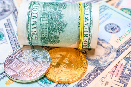 Bitcoins on the background of one hundred dollar bills, close-upの写真素材
