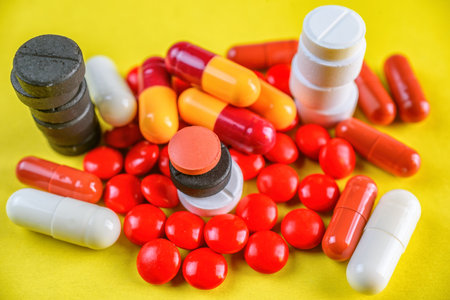 Pills and capsules on yellow background. Focus on foreground, soft bokeh.の写真素材