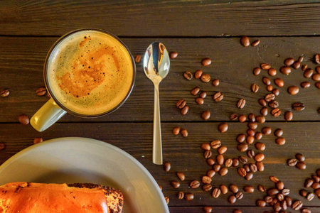 Buns with poppy seeds on a gray plate and coffee mug on a black wooden background. Near coffee beans