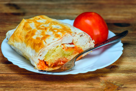 Pita bread stuffed with chicken and vegetables on a wooden table.の写真素材
