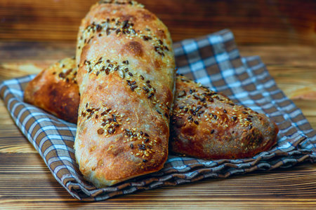 Freshly baked bread with sesame seeds on a wooden background.の写真素材