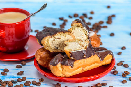 Chocolate eclairs and cup of coffee on blue wooden backgroundの写真素材