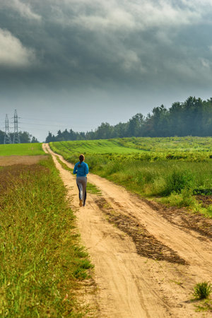 girl runs on a field roadの写真素材