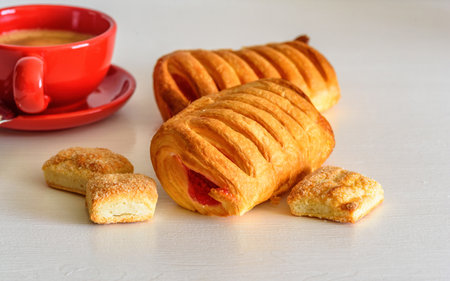 Puff pastry with jam and coffee mug on a white wooden backgroundの写真素材
