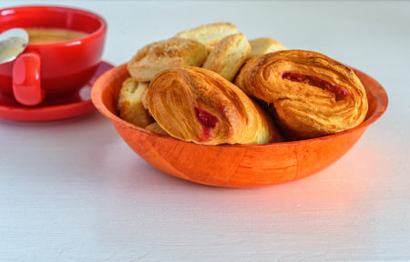 Puff pastry with jam and coffee mug on a white wooden backgroundの写真素材