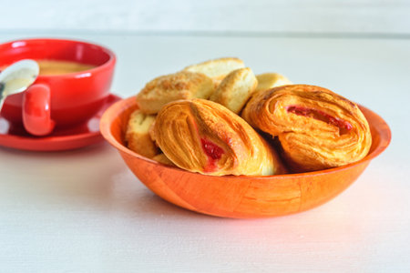 Puff pastry with jam and coffee mug on a white wooden backgroundの写真素材