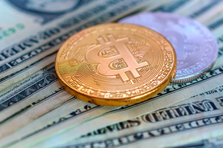 golden bitcoin coin on the background of one hundred dollar bills.の写真素材