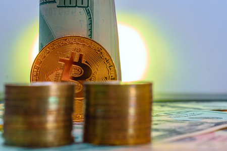 golden bitcoin coin on the background of dollar bills and a candleの写真素材