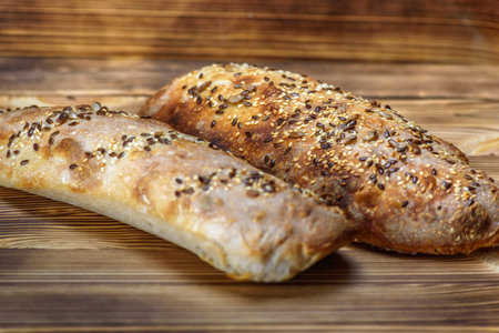 Freshly baked baguette with sesame seeds on wooden table