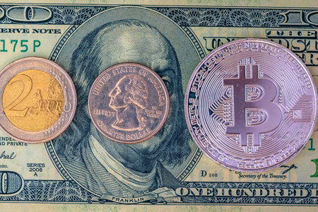 Golden bitcoin on the background of one hundred dollar bills. Close-up.の写真素材