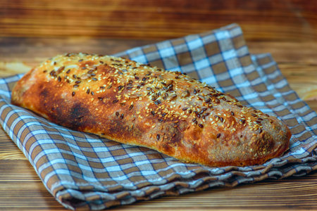 Freshly baked bread with sesame seeds on a wooden background.