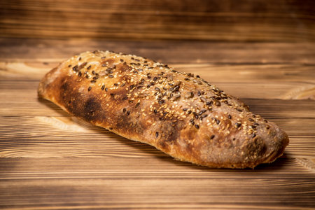 Freshly baked bread with sesame seeds on rustic wooden tableの写真素材