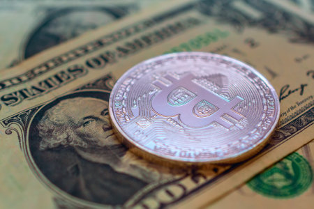 Bitcoin coin on the background of one hundred dollar bills. Digital currency.の写真素材
