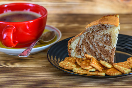 Coffee cup and crackers on saucer on wooden table.の写真素材