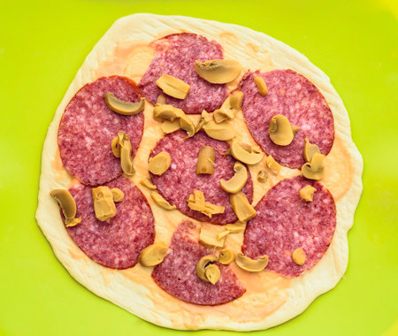 pizza with salami and mushrooms on a green background, top viewの写真素材